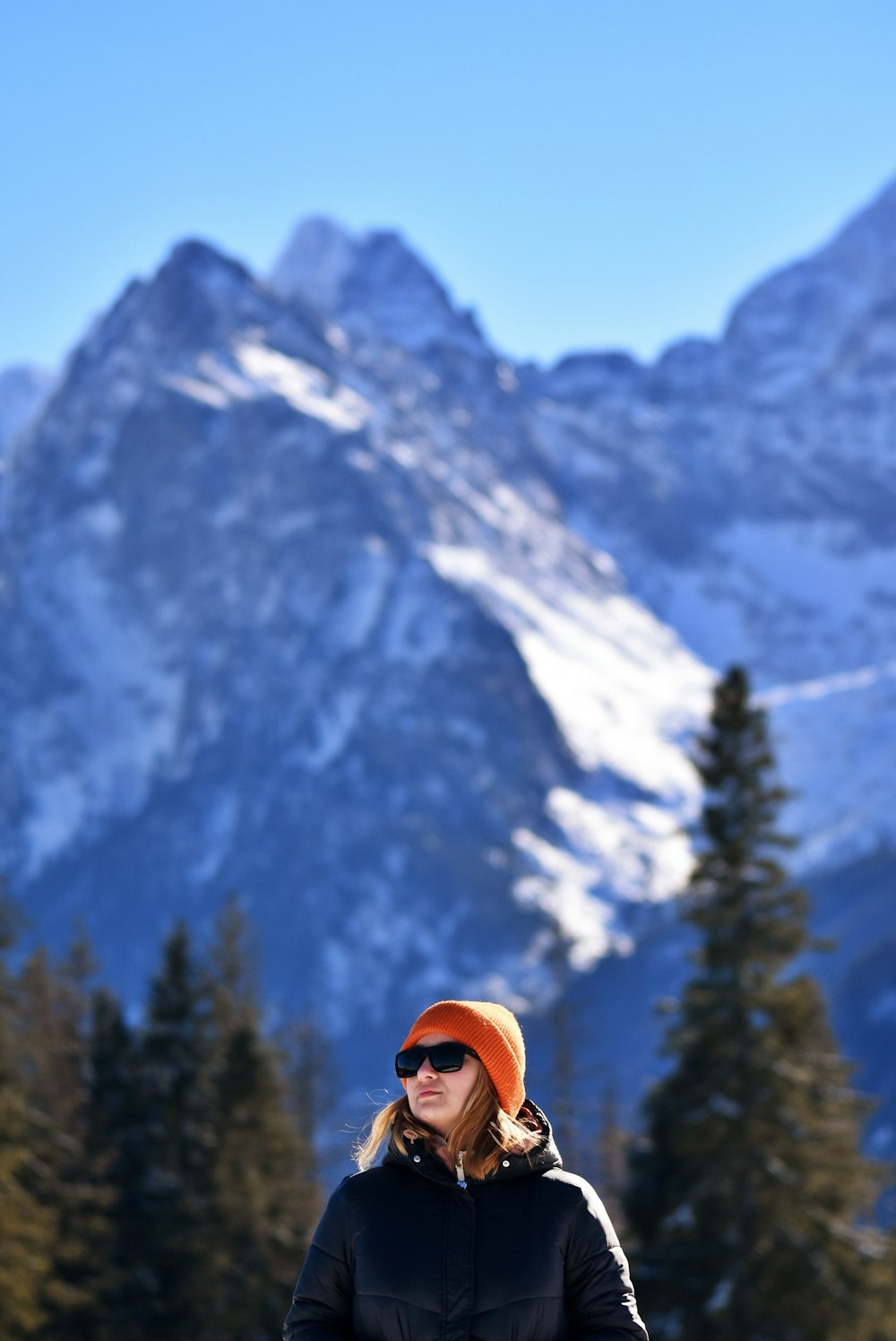 uma mulher em pé no topo de uma encosta coberta de neve