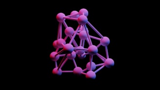 A 3D geometric structure consisting of interconnected spheres and rods resembles a molecular model or network. The spheres are primarily pink with hints of purple and blue, set against a black background, creating a striking contrast.