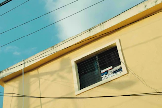 a yellow building with a window and power lines