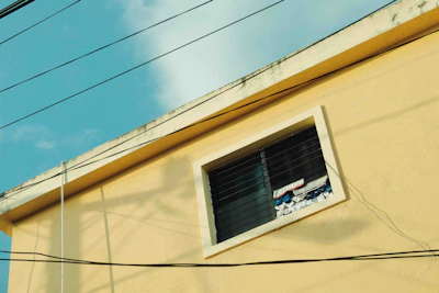 a yellow building with a window and power lines