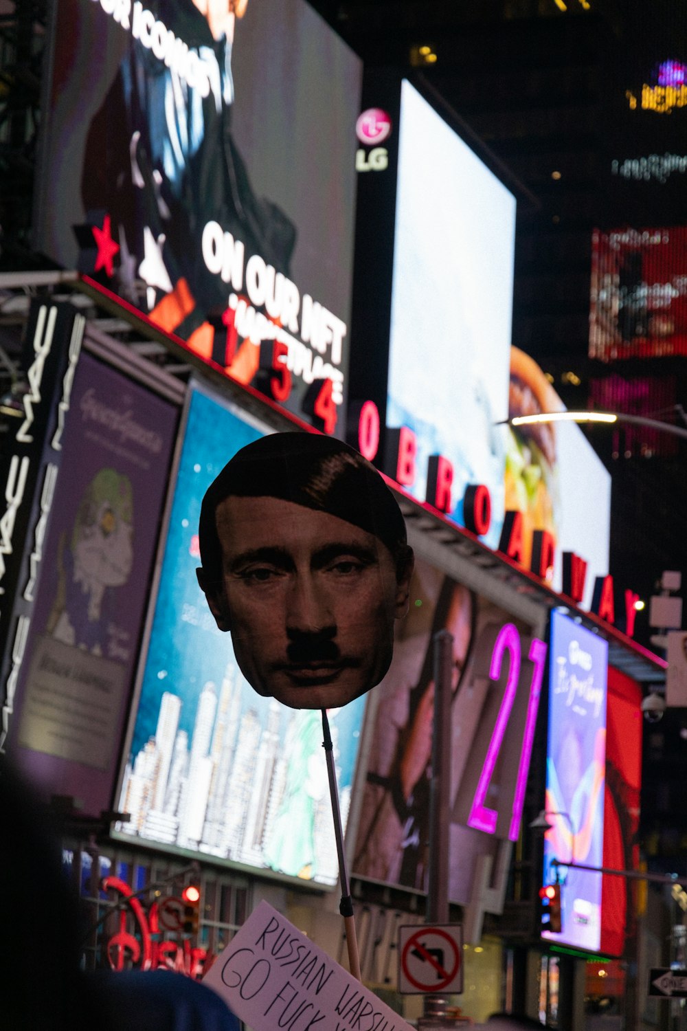 a busturine of a man holding a sign in front of billboards