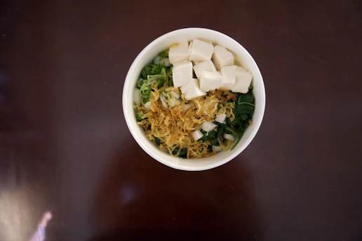 A vibrant curry bowl featuring moong dal tofu, colorful spices, and fresh greens.