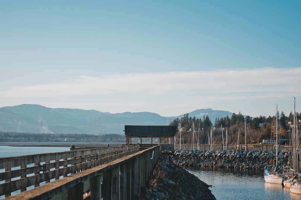 a pier with a boat in the water and mountains in the background