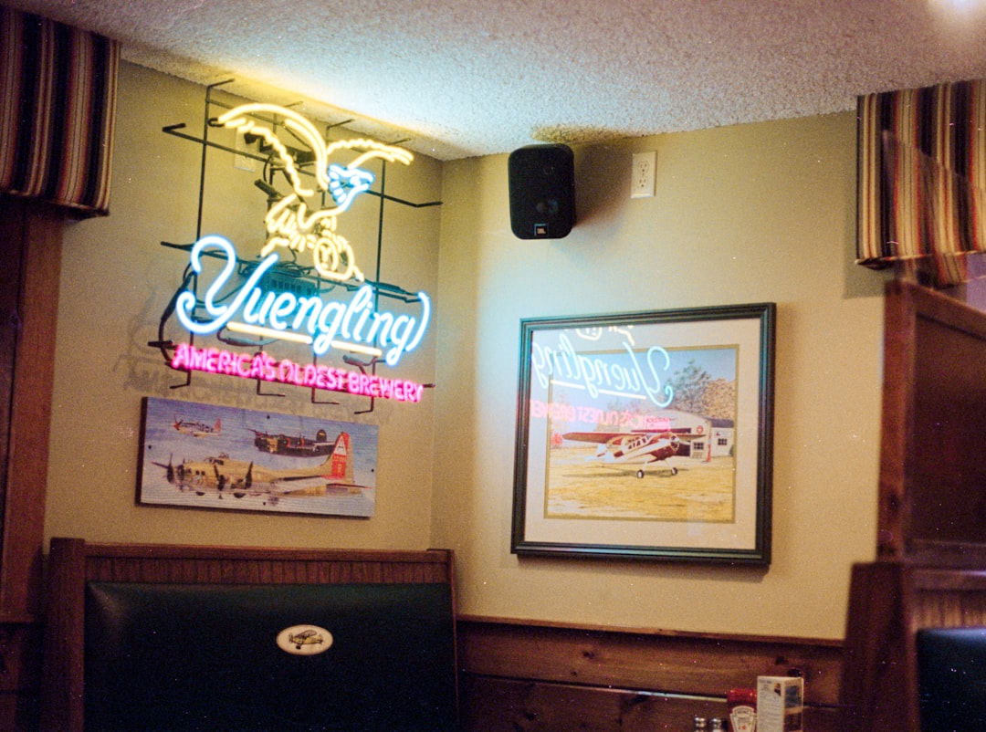a restaurant with a neon sign on the wall, Shot on Canon AE-1 with Kodak Gold 200 film