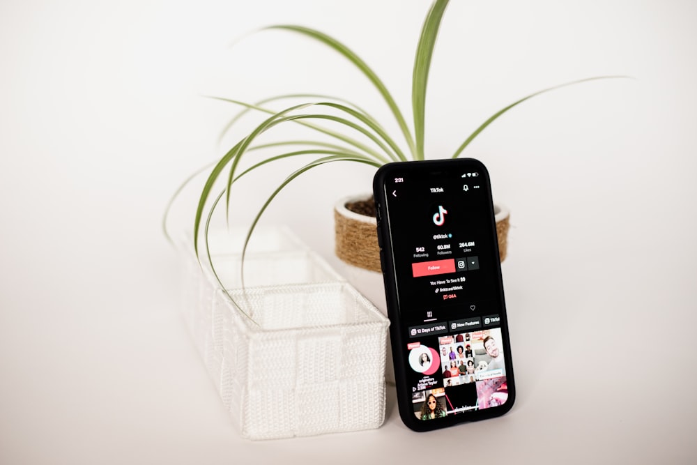 a cell phone sitting on top of a table next to a plant