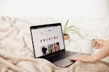 a woman is holding a coffee cup and looking at her laptop