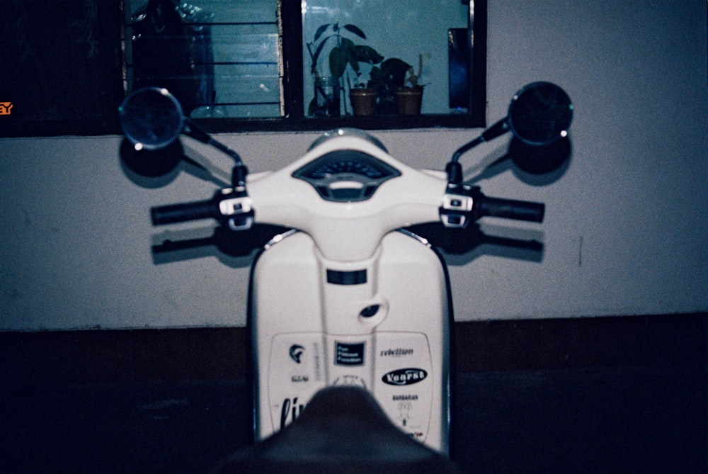 a white scooter parked in front of a window