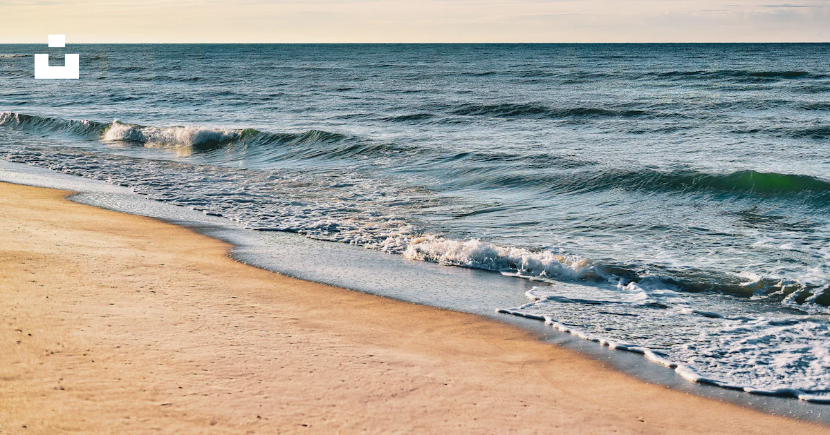 Une plage de sable avec des vagues qui arrivent sur le rivage photo ...