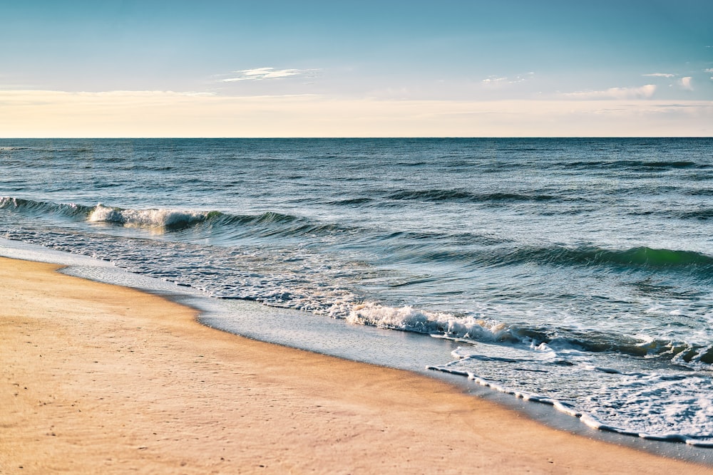 uma praia de areia com ondas que chegam à costa