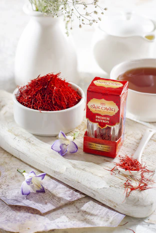Close-up of deep red saffron threads resting delicately on a gold-rimmed green ceramic dish.
