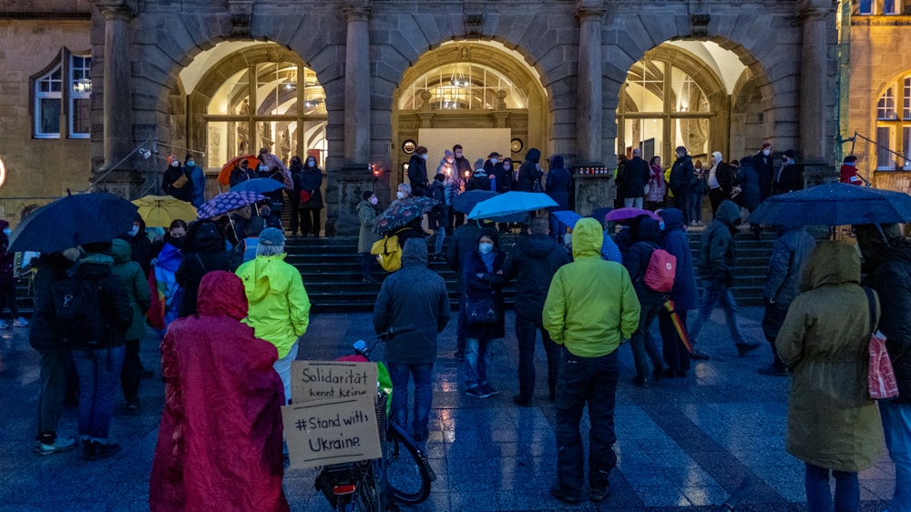 Eine Gruppe von Menschen mit Regenschirmen vor einem Gebäude