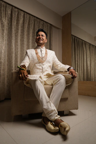 a man in a white suit sitting in a chair