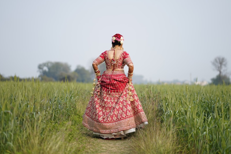 a woman in a red dress walking through tall grass