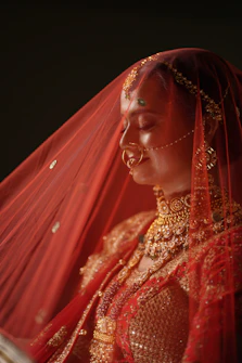 a woman wearing a red veil and gold jewelry