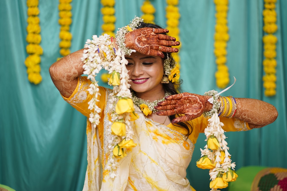 a woman in a yellow and white sari holding her hands up to her face