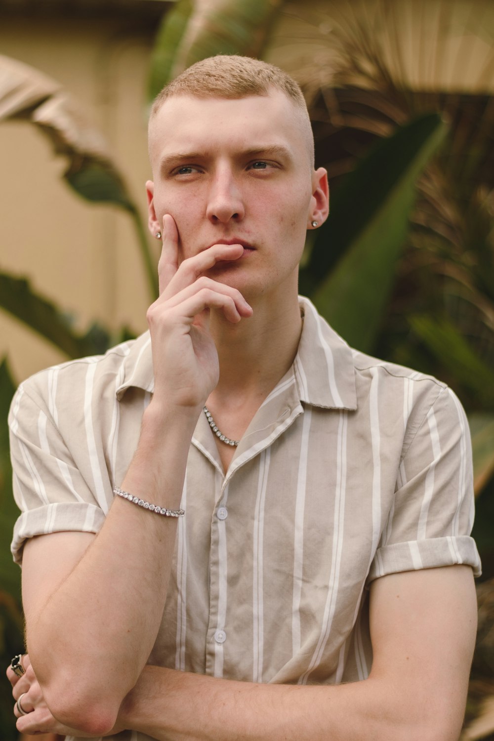 a young man poses for a picture with his hand on his chin