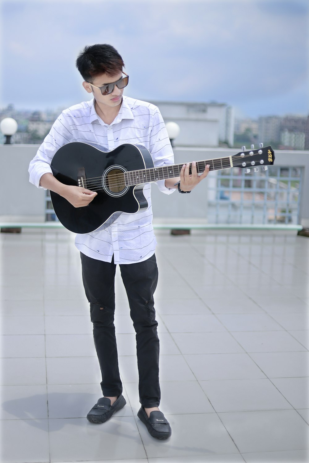 a man holding a guitar on top of a roof