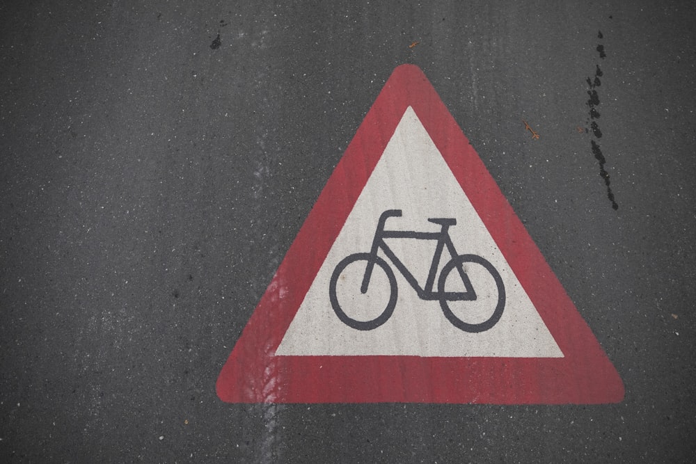 a red and white triangle sign with a bicycle on it