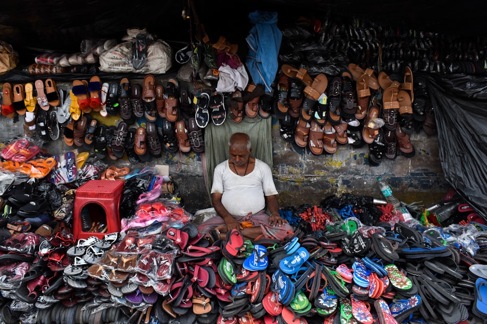 a man sitting in front of a pile of shoes