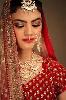 a woman wearing a red and gold bridal outfit