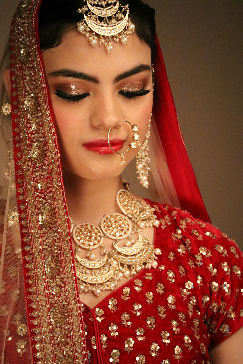 a woman wearing a red and gold bridal outfit