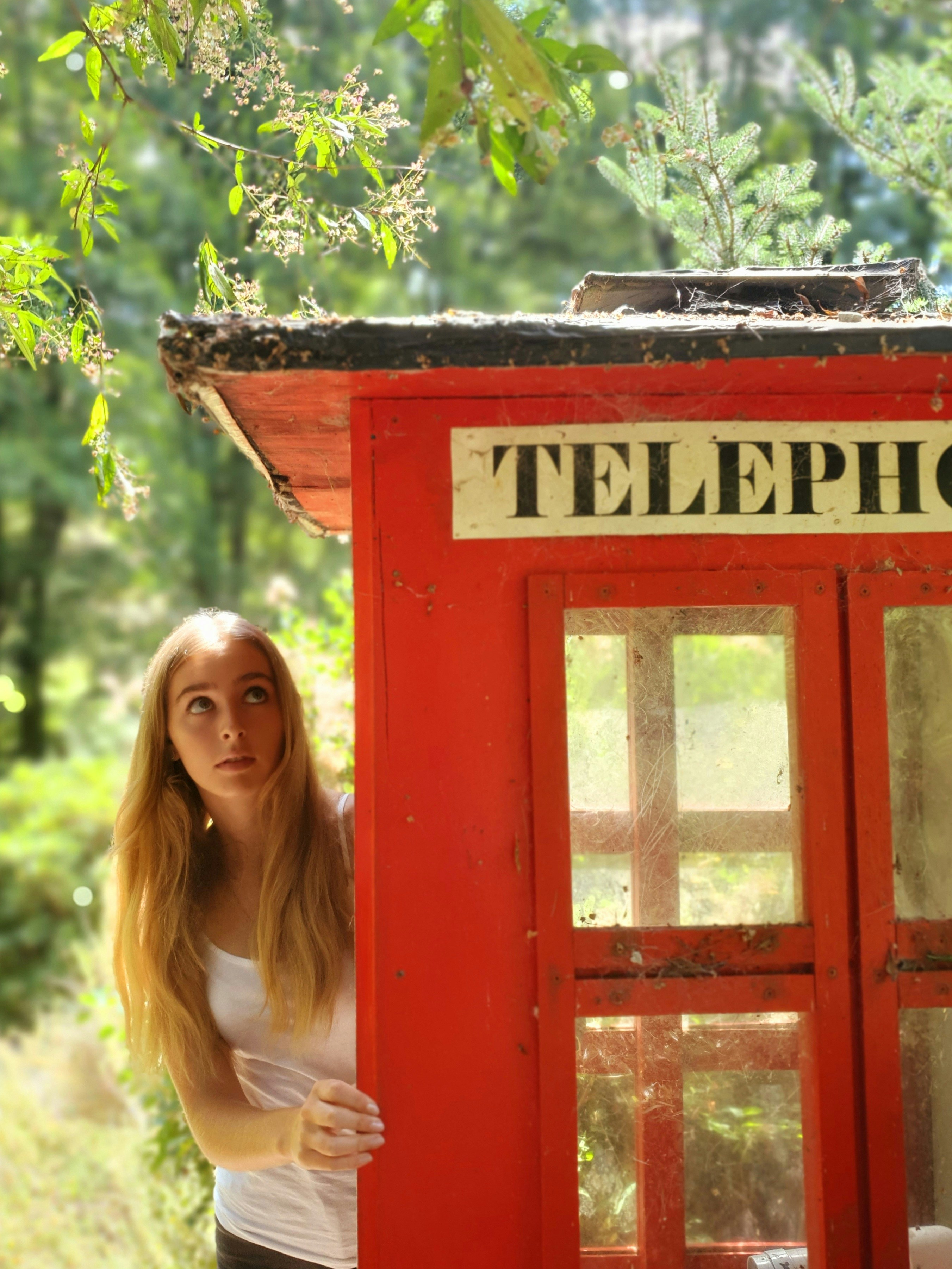 a woman standing in front of a red phone booth