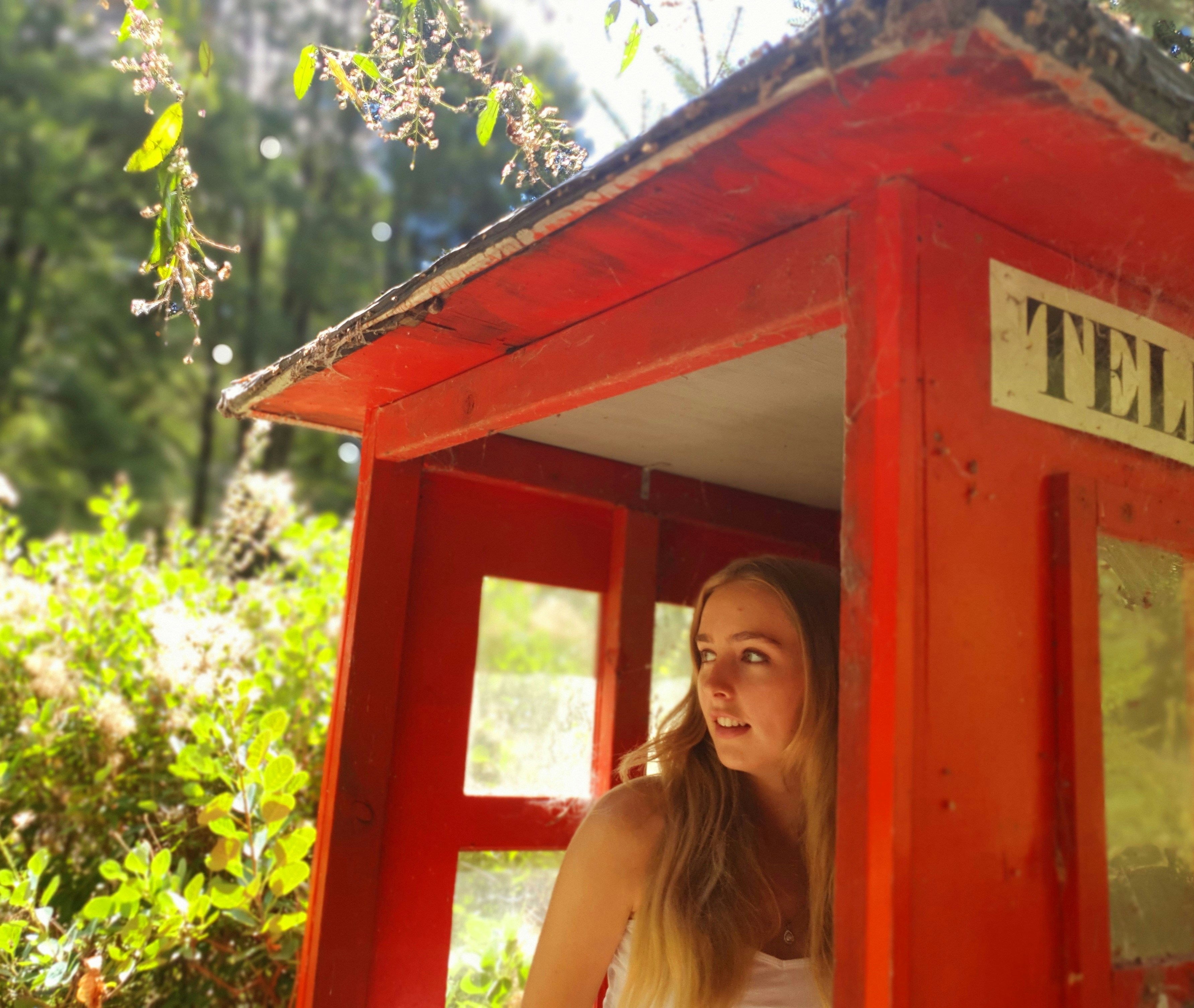 a woman standing inside of a red phone booth