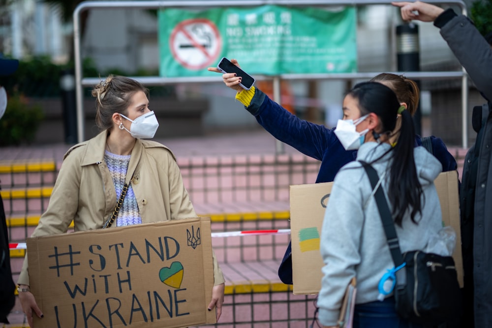 a group of people holding signs and wearing masks