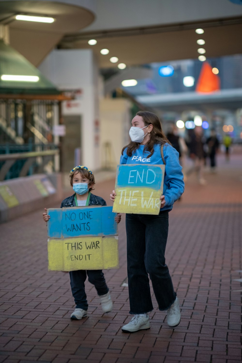 a woman and a child wearing masks holding signs