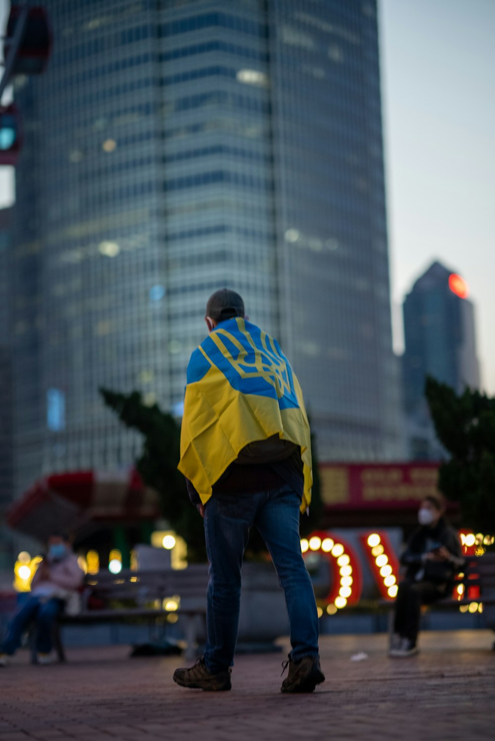 a man in a yellow and blue jacket is standing in front of a tall building