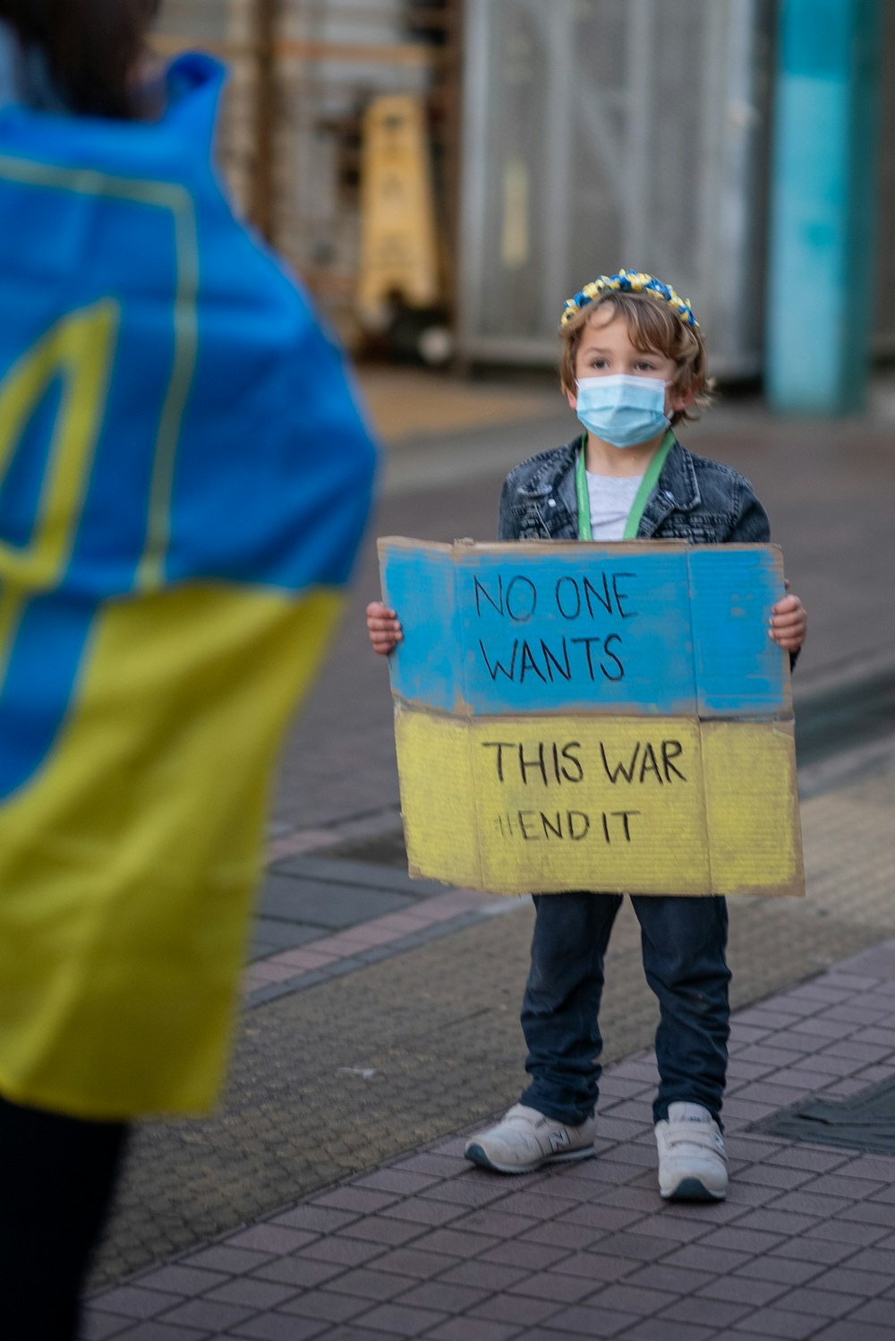 Una niña pequeña sosteniendo un cartel que dice que nadie quiere esta guerra y