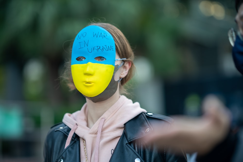 uma mulher com um rosto pintado vestindo uma máscara azul e amarela