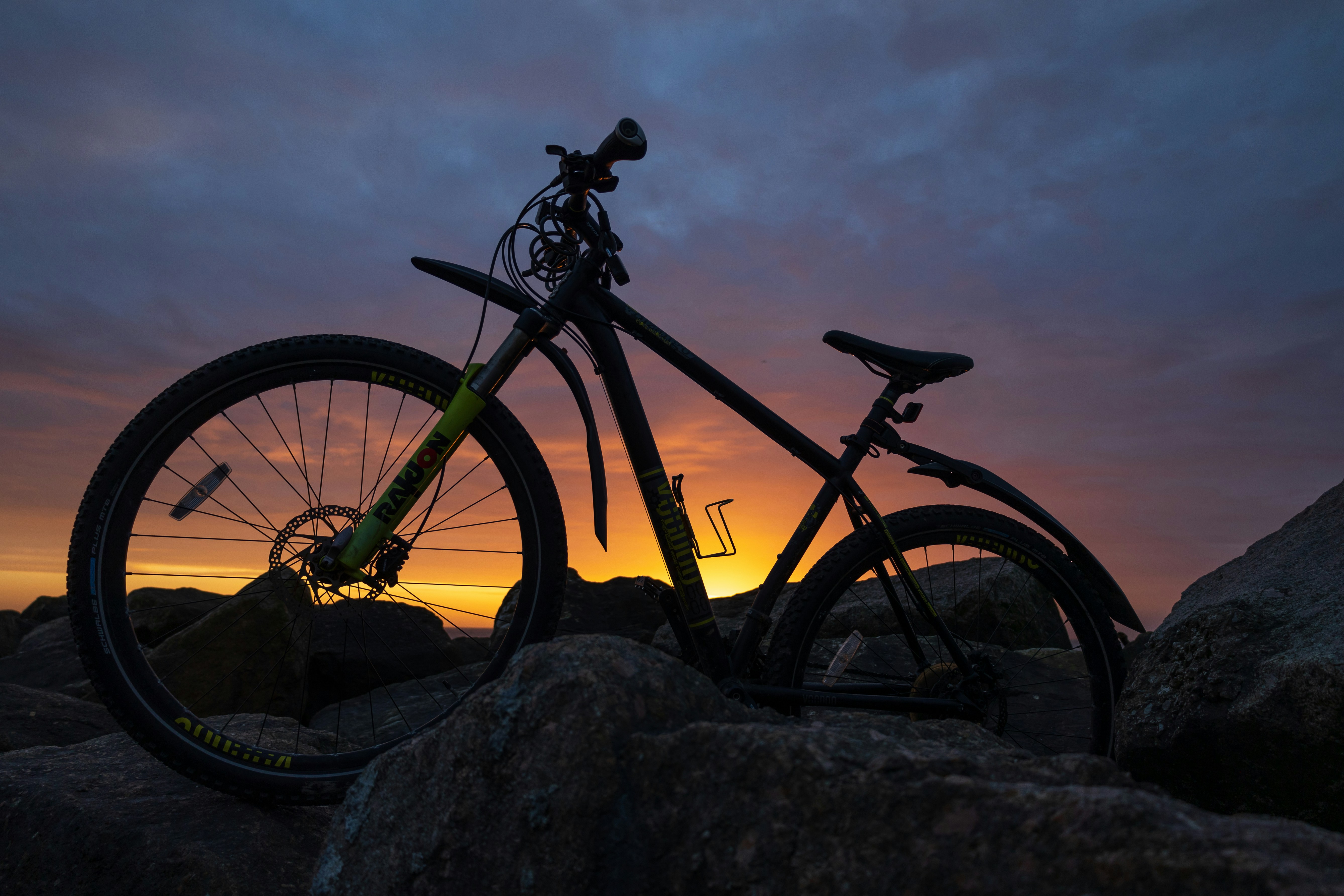 a bike is sitting on some rocks at sunset