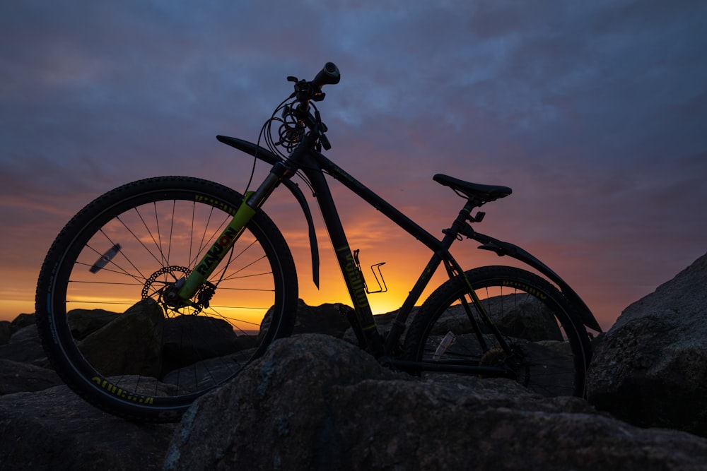 a bike is sitting on some rocks at sunset