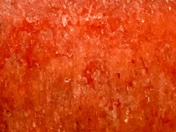 a close up of a red wall with a clock on it