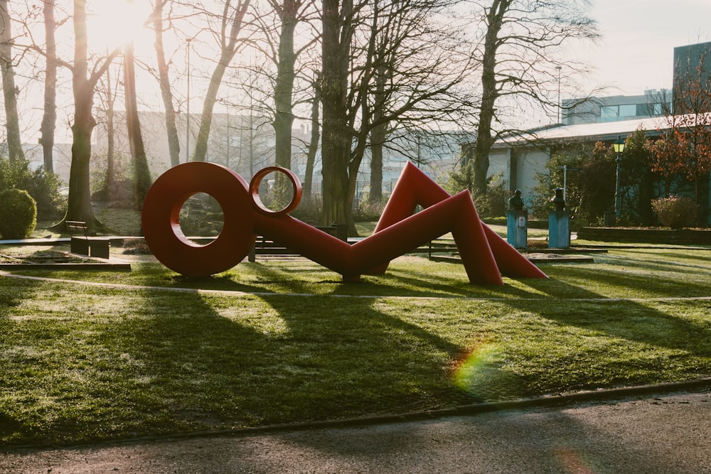 a large red sculpture sitting on top of a lush green field