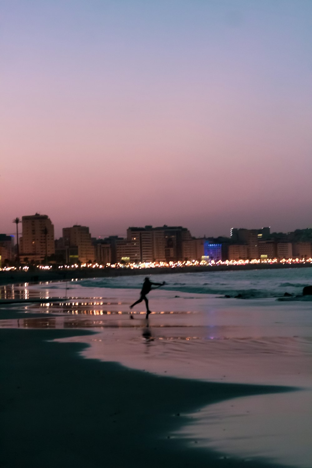 uma pessoa andando em uma praia com uma cidade no fundo