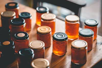 A bench of amber jam jars cooling under a window