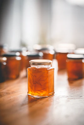 Handcrafted glass jars filled with vibrant homemade marmellata, arranged on a wooden table outdoors