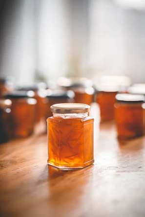 Close-up of artisanal Spanish jam jars on a rustic wooden table with warm natural light.