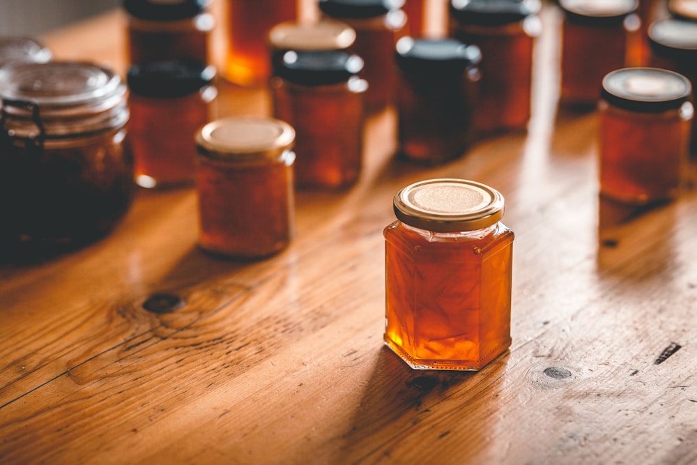 a wooden table topped with lots of jars of honey