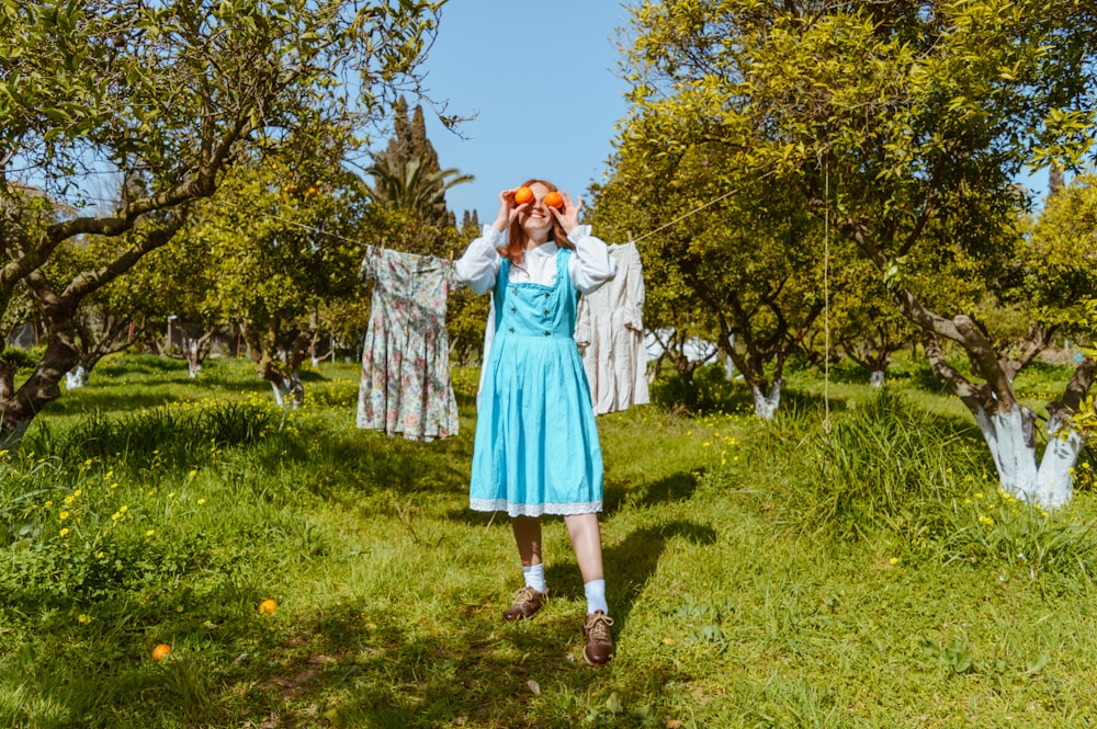 a woman in a blue dress standing in an apple orchard