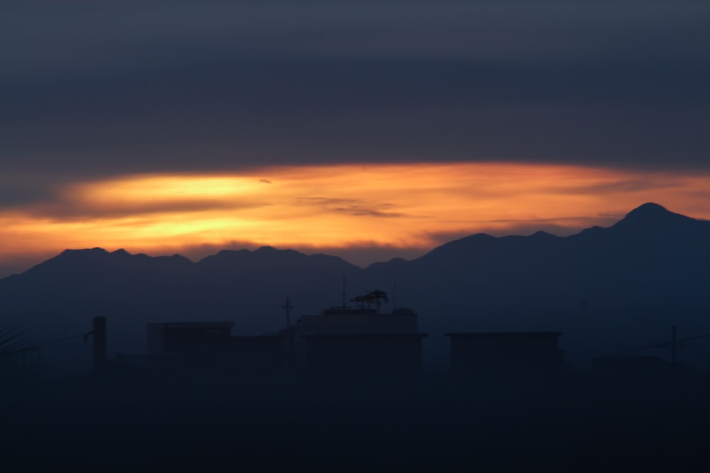 the sun is setting over a mountain range