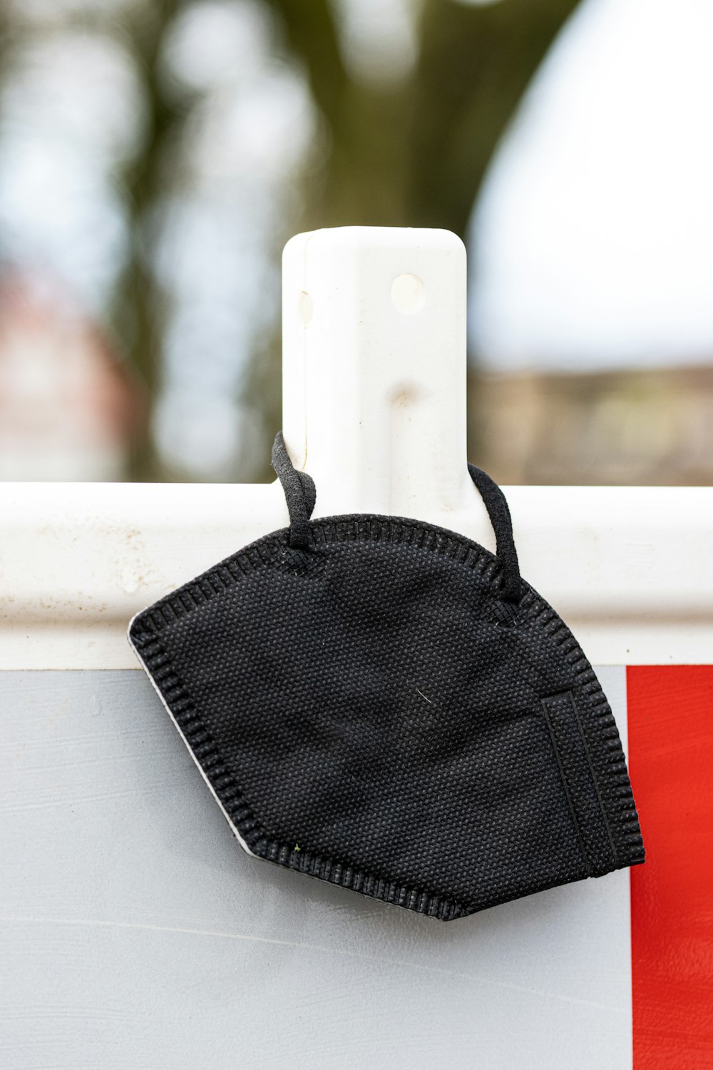 a black face mask hanging on the side of a fence