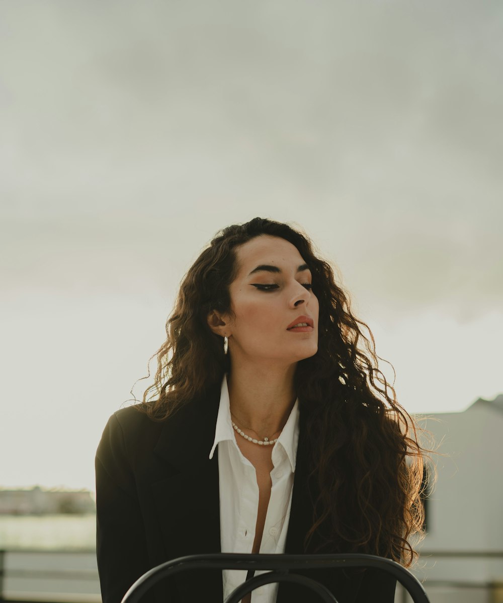 a woman with long hair wearing a black jacket and white shirt