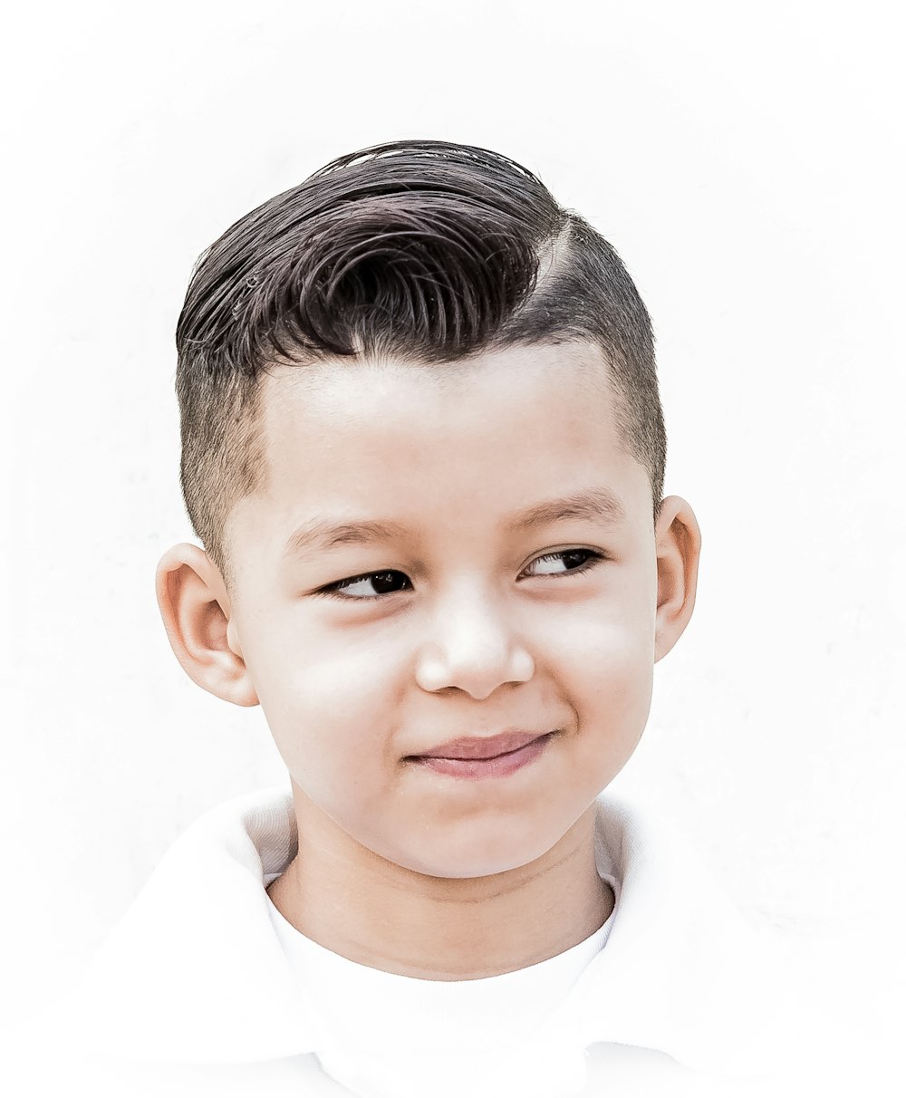 a young boy with a short haircut and a white shirt