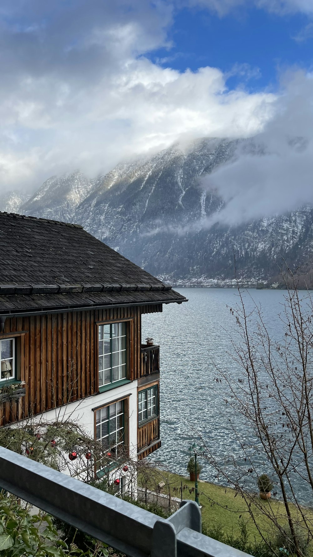 a house next to a body of water with mountains in the background