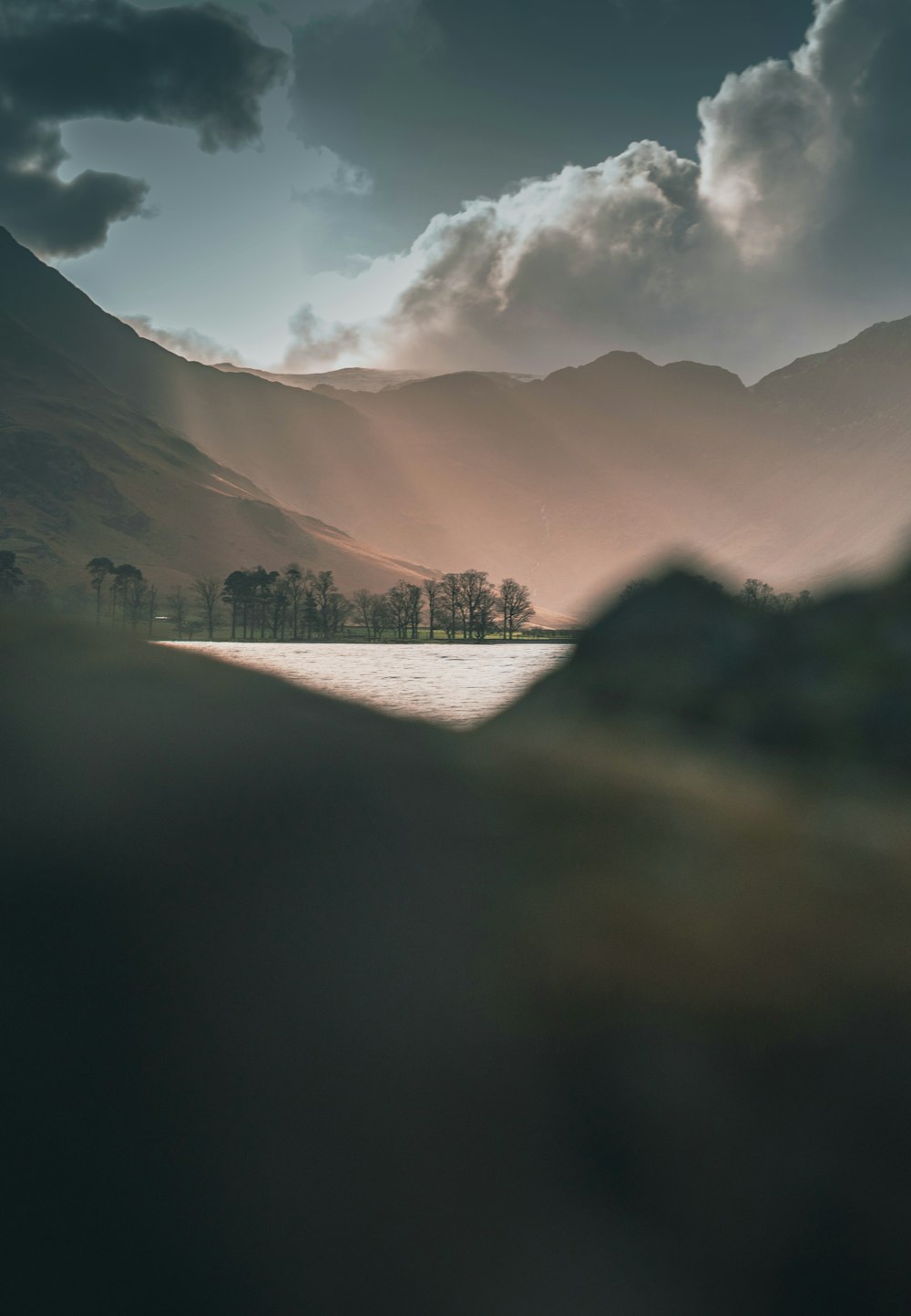 a lake with mountains in the background under a cloudy sky