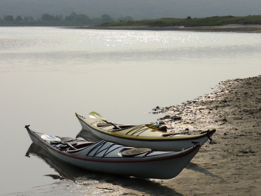 two canoes sitting on the shore of a lake