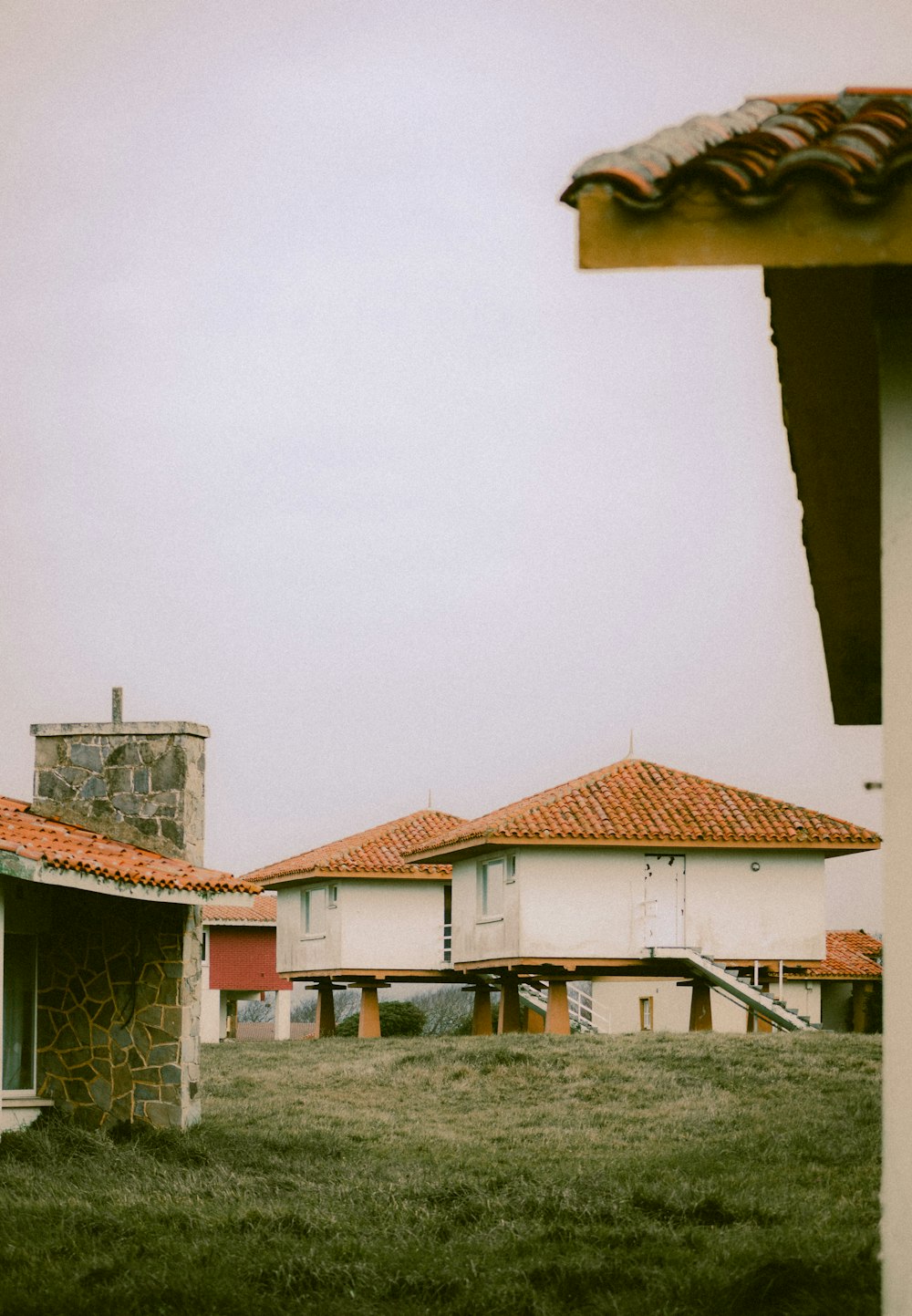 a couple of houses sitting on top of a lush green field